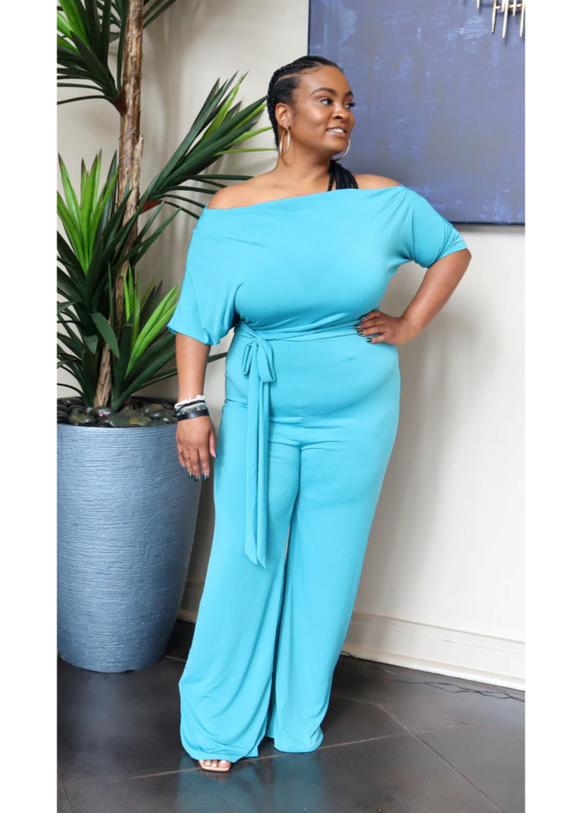 Stretchy off-shoulder jumpsuit with a belted waistline and wide legs. Model is 5'3, 205 lbs, wearing a size 1X.